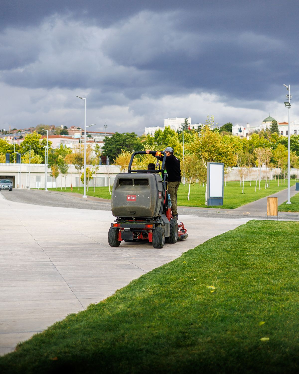 Commercial landscaping crew operating a riding lawn mower in a park